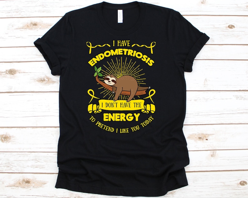 May include: Black t-shirt with a sloth graphic and the text "I HAVE ENDOMETRIOSIS I DON'T HAVE THE ENERGY to pretend I like you today." The sloth is brown and resting on a tree branch. Yellow ribbons and sunburst design elements are included.