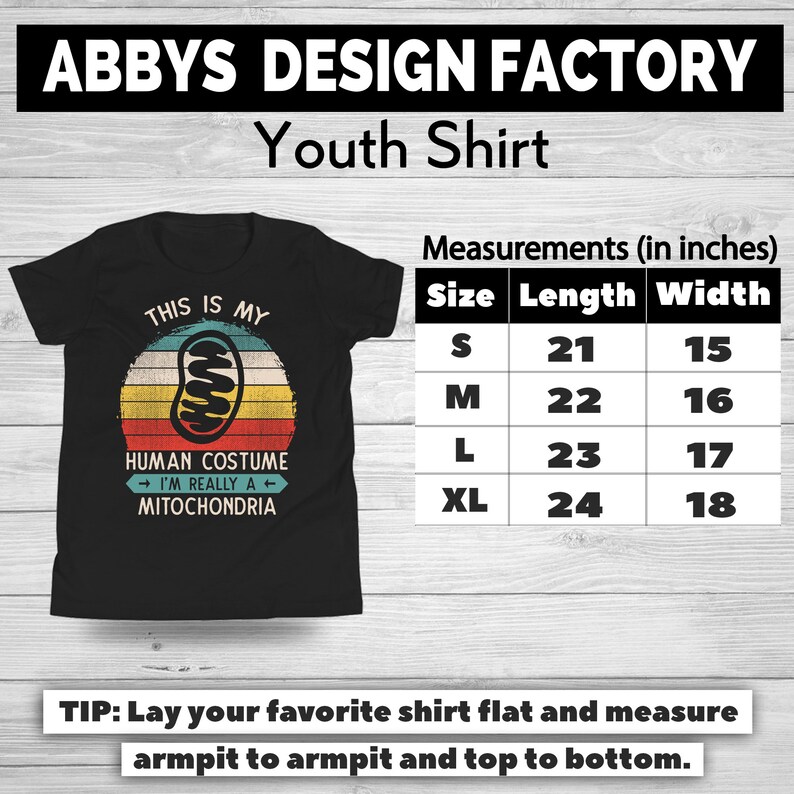 May include: Black youth shirt with a retro design. The shirt features a mitochondria graphic inside a sunset circle, with the text "THIS IS MY HUMAN COSTUME I'M REALLY A MITOCHONDRIA." Measurements are provided in inches: S (21" length, 15" width), M (22" length, 16" width), L (23" length, 17" width), XL (24" length, 18" width).