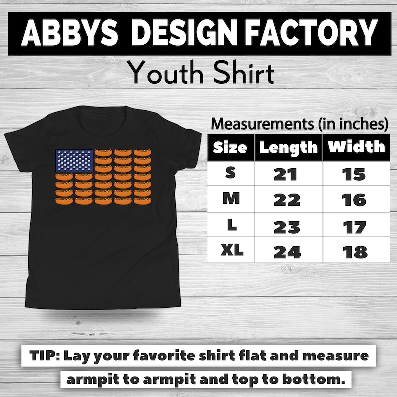 May include: Black youth shirt featuring a design of the American flag made of hot dogs. The shirt includes a size chart with measurements in inches. The text "ABBYS DESIGN FACTORY Youth Shirt" is at the top.