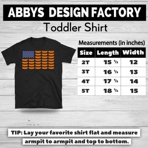 May include: Black toddler shirt with a graphic of an American flag made of hot dogs. The shirt has the text "ABBY'S DESIGN FACTORY Toddler Shirt". Measurements are provided in inches for sizes 2T to 5T.