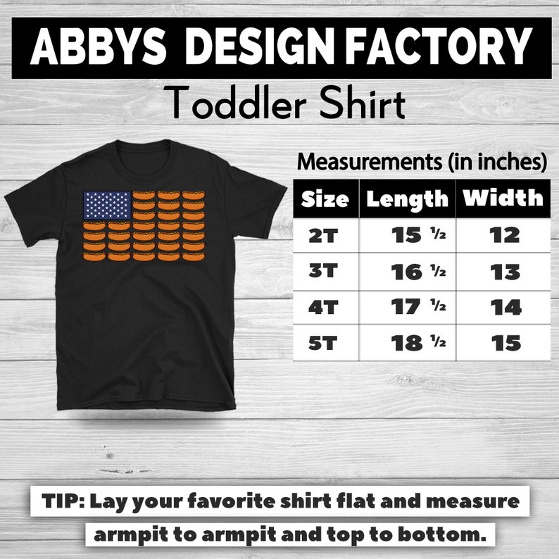 May include: Black toddler shirt with a graphic of an American flag made of hot dogs. The shirt has the text "ABBY'S DESIGN FACTORY Toddler Shirt". Measurements are provided in inches for sizes 2T to 5T.