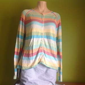 May include: A striped cardigan with long sleeves and a button-up front. The cardigan is made of a soft, lightweight fabric and features a variety of colors, including pink, blue, yellow, and green.