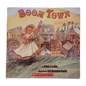 May include: A children's book cover titled "Boom Town" with a watercolor illustration. The image features a girl holding a pie, waving in front of a town scene. The author is Sonia Levitin, and the illustrator is Cat Bowman Smith.