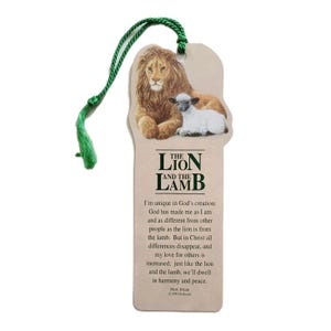 May include: A bookmark featuring an illustration of a lion and a lamb. The bookmark has a green cord and text that reads "The Lion and the Lamb". The lion is brown and the lamb is white. The bookmark is beige.