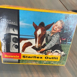 May include: Vintage Kodak Brownie Starflex Outfit box. The box features a photograph of a child with a foal. The box is yellow with black and red text. The camera is visible on the left side of the box.