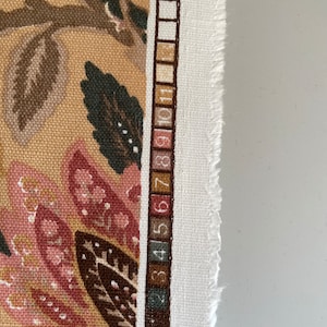 Puede incluir: Primer plano de una tela con un patr&oacute;n floral en tonos marrones, rosas y blancos. A la derecha de la imagen se puede ver una tabla de colores con los n&uacute;meros del 1 al 11.