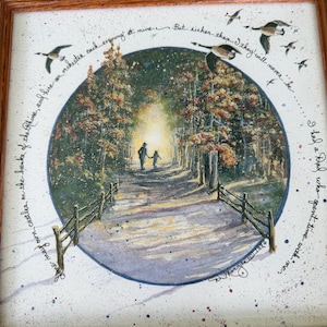May include: A framed square print featuring a circular painting of two figures walking down a path between trees toward a bright light. The scene includes a wooden fence, flying birds, and cursive text surrounding the circle, signed by D. Morgan.
