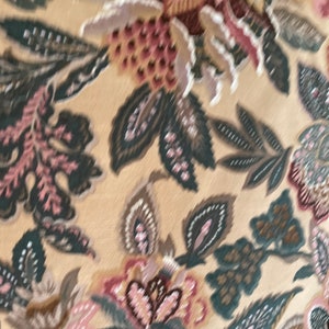 Puede incluir: Una tela beige con un patr&oacute;n floral en tonos de rosa, marr&oacute;n y verde. El patr&oacute;n presenta flores y hojas estilizadas.