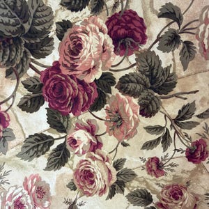 May include: A fabric pattern featuring clusters of blooming roses in shades of deep burgundy, soft pink, and cream. The floral design is accented by dark olive green leaves and stems, set against a light beige background with a subtle marble texture.