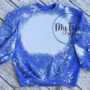Puede incluir: Una sudadera azul con un diseño de círculo blanco blanqueado. La sudadera tiene cuello redondo y mangas largas. El texto "My Five Designs" está en un círculo en el lado derecho de la sudadera.