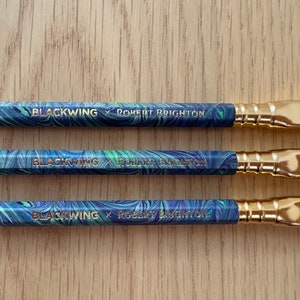 May include: Three black and green marbled pencils with gold accents and purple erasers. The pencils are labeled "Blackwing x Robert Brighton".
