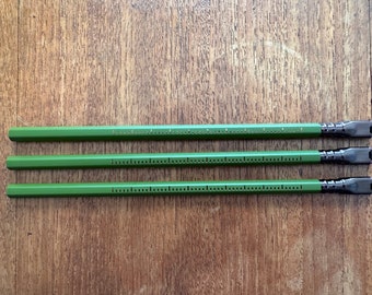 May include: Three green hexagonal pencils with black and brown erasers. The pencils have a ruler printed on the side.
