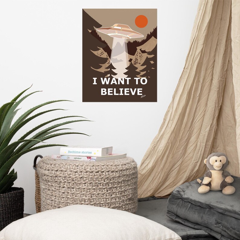 Op de afbeelding: Een bruine en beige poster met een UFO die over een bos vliegt. De poster heeft de tekst "I WANT TO BELIEVE" in witte letters.