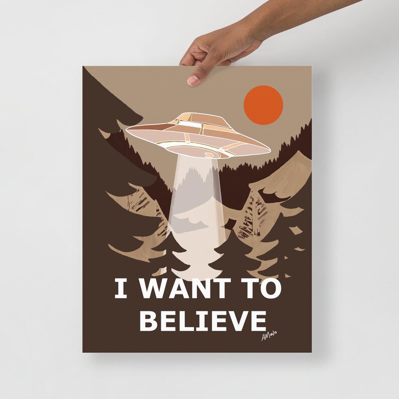 Op de afbeelding: Een poster in retro-stijl met een bruine achtergrond waarop een vliegende schotel boven een bos te zien is met de tekst "I WANT TO BELIEVE".