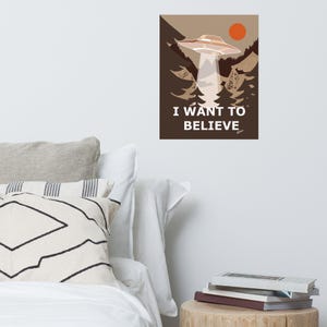 Op de afbeelding: Een bruine en witte poster met een UFO die over een bos vliegt. De poster zegt "Ik wil geloven".