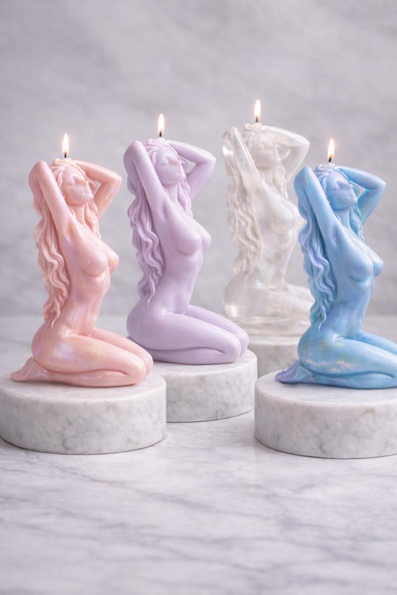 Puede incluir: Cuatro velas esculpidas con forma de figura arrodillada de pelo largo, cada una sobre una base circular de m&aacute;rmol blanco. Las velas son de color rosa claro, lavanda, blanco y azul claro, con una mecha encendida en la parte superior.