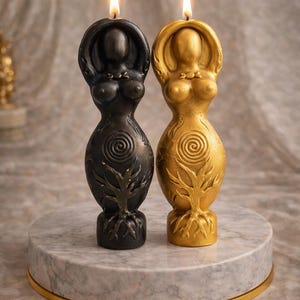 May include: Two lit, stylized goddess candles, one black and one gold, stand on a marble base with a gold rim. The candles feature a tree of life design and a spiral on the torso. The candles are a decorative item.