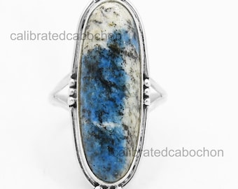 May include: A silver ring featuring an oval k2 stone. The stone has a mix of white, blue, and black patterns. The ring has a detailed silver setting with a decorative edge and a split shank design.