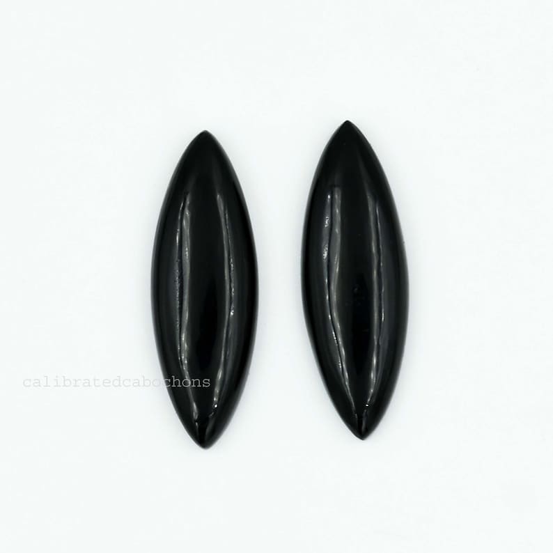 Pu&ograve; includere: Due cabochon ovali neri lucidi. I cabochon sono lisci e hanno una finitura lucida.