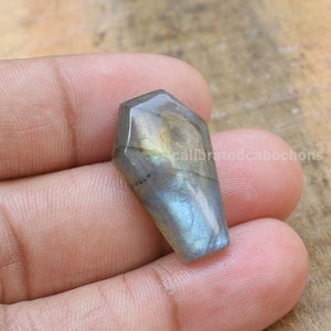 May include: A gray, green, and gold labradorite cabochon with a faceted, teardrop shape.