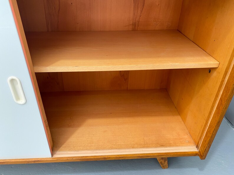 Peut inclure: Une armoire bleu clair avec un int&eacute;rieur en bois. L'armoire a deux &eacute;tag&egrave;res et une seule porte avec une poign&eacute;e blanche.