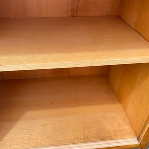 Peut inclure: Une armoire en bois avec deux &eacute;tag&egrave;res. Les &eacute;tag&egrave;res sont vides et en bois clair. L'armoire est en bois fonc&eacute; et a une porte en verre.