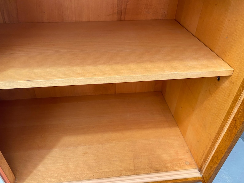 Peut inclure: Une armoire en bois avec deux &eacute;tag&egrave;res. Les &eacute;tag&egrave;res sont vides et en bois clair. L'armoire est en bois fonc&eacute; et a une porte en verre.