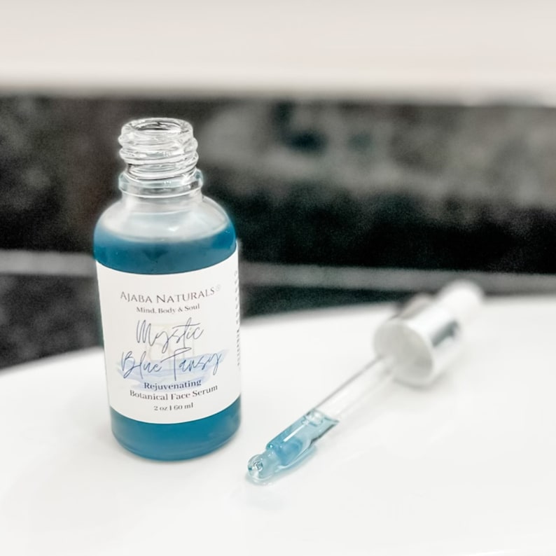 May include: A blue glass bottle with a dropper, labeled "Mystic Blue Tansy Rejuvenating Botanical Face Serum 2 oz / 60 ml" by Aiara Naturals.