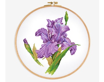 Könnte beinhalten: Eine gestickte Iris-Blume in Lila- und Grüntönen, in einem hölzernen Stickrahmen ausgestellt.