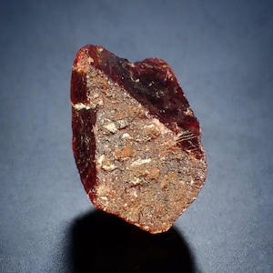 Peut inclure: Une pierre précieuse brute, brun rougeâtre, avec une structure cristalline. La pierre a un aspect sombre et translucide avec des zones plus claires et texturées. La surface a une texture rugueuse et inégale, et la forme générale est irrégulière.