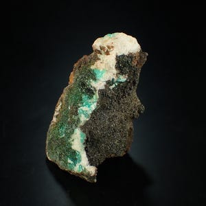 May include: A green and white mineral specimen on a black background. The mineral has a rough, textured surface and is a natural formation.