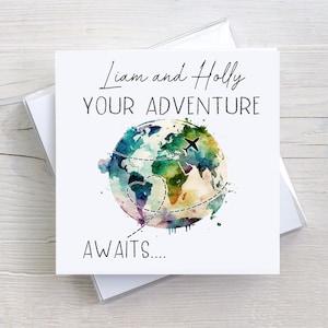 May include: A white card with the text "Liam and Holly Your Adventure Awaits..." in black script. A watercolour painting of a globe with a heart and a plane flying over it.