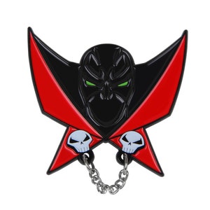 Pode incluir: Pin de esmalte preto e vermelho com um super-herói com uma caveira e uma corrente. O super-herói usa uma capa preta e tem olhos verdes.