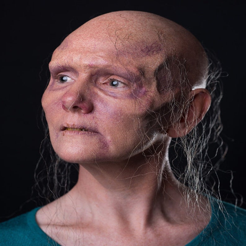 Pu&ograve; includere: Un ritratto ravvicinato di una persona con la testa rasata e un incarnato pallido. La persona ha un viso rugoso con vene visibili e guarda in alto e a destra. La persona ha capelli lunghi e bianchi che le cadono sul viso e sul collo.