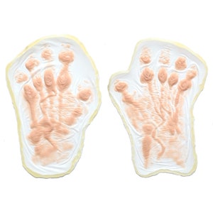 Puede incluir: Dos moldes en forma de mano beige con una superficie texturizada, perfectos para crear huellas de manos realistas para maquillaje de efectos especiales o disfraces de Halloween.