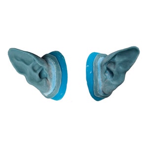 May include: A pair of blue ear moulds with a blue base. The ear moulds are made of a soft, flexible material and are designed to fit comfortably in the ear.