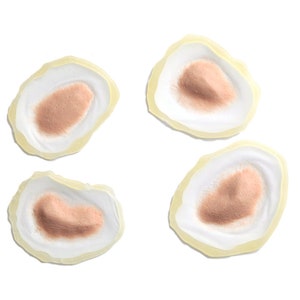 Puede incluir: Cuatro piezas de maquillaje protésico de silicona beige y blanco para crear heridas falsas. Cada pieza tiene un centro elevado y texturizado.
