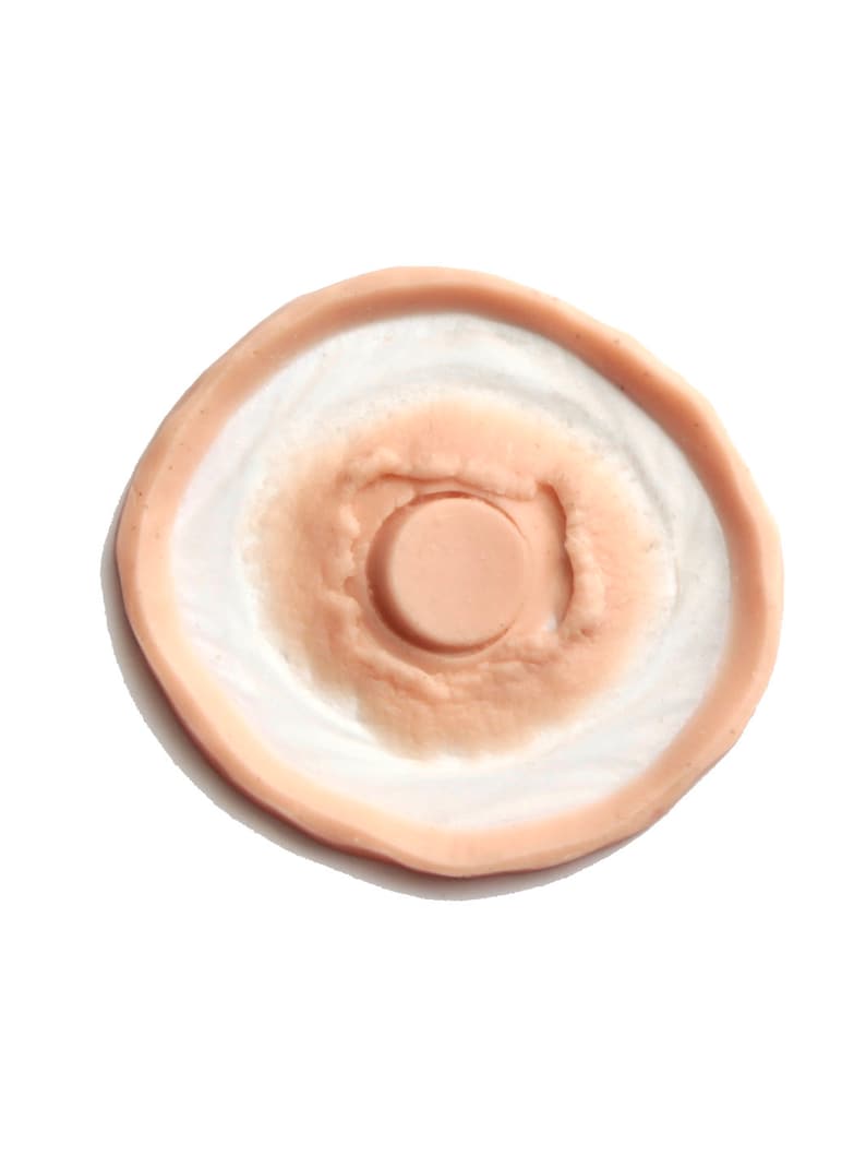 Op de afbeelding: Een ronde, huidkleurige siliconen mal met een verhoogd, cirkelvormig ontwerp in het midden. De mal is ontworpen om realistisch ogende nep-wonden te cre&euml;ren.