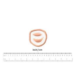 Puede incluir: Primer plano de un peque&ntilde;o molde de silicona redondo de color carne con dos impresiones ovaladas en relieve. El molde est&aacute; dise&ntilde;ado para crear heridas de aspecto realista para el maquillaje de efectos especiales.