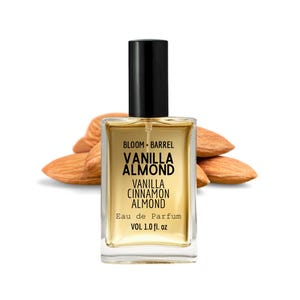 May include: A rectangular perfume bottle with a black cap, labeled "BLOOM + BARREL VANILLA ALMOND VANILLA CINNAMON ALMOND Eau de Parfum VOL 1.0 fl. oz." The bottle is filled with a light amber liquid, and is set against a backdrop of almonds.