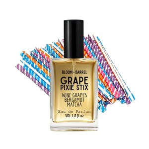 May include: A rectangular perfume bottle with a black cap and a gold-colored liquid. The label reads "GRAPE PIXIE STIX" with "WINE GRAPES BERGAMOT MATCHA" below. The bottle is 1.0 fl. oz. and is set against a backdrop of colorful, striped paper.