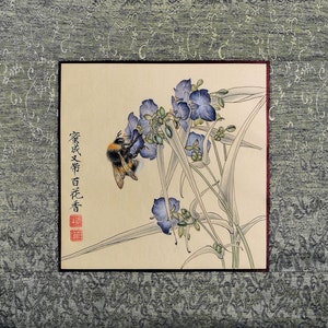 K&ouml;nnte beinhalten: Ein traditionelles chinesisches Gem&auml;lde, das eine Hummel zeigt, die eine Gruppe von lila Bl&uuml;ten best&auml;ubt. Das Gem&auml;lde ist gerahmt und enth&auml;lt den Text "繁花次第百花香" in chinesischen Schriftzeichen.