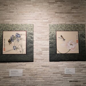 K&ouml;nnte beinhalten: Zwei gerahmte asiatische Gem&auml;lde an einer wei&szlig;en Backsteinwand. Das linke Gem&auml;lde zeigt eine Biene auf einer Blume mit chinesischen Schriftzeichen. Das rechte Gem&auml;lde zeigt eine Libelle auf einer Lotusblume mit chinesischen Schriftzeichen.