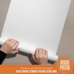 Op de afbeelding: Een witte poster opgerold en vastgehouden door twee handen. De poster is gelabeld "Deluxe Poster" in oranje tekst. De tekst "Premium grade fine art paper DIGITAL PRINTING TECHNOLOGY FOR LONG LASTING COLORS" is onder het label gedrukt.