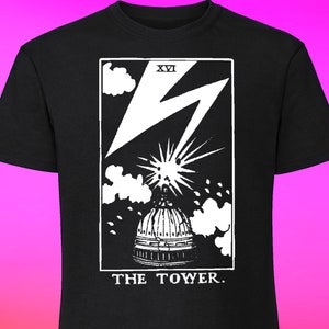 May include: Black t-shirt with a white graphic of the Tower card from a tarot deck. The card shows a lightning bolt striking a building with a dome. The text "XVI THE TOWER." is printed below the image.