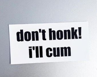 Può includere: Adesivo rettangolare bianco con la scritta "don't honk! I'll cum" in nero in grassetto. L'adesivo è posizionato su una superficie grigio chiaro.