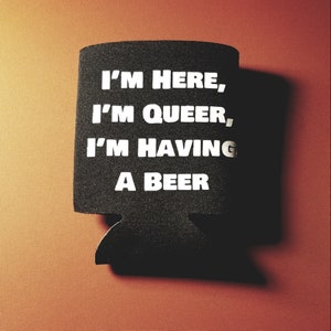 May include: Black foam cooler with the text "I'm here, I'm queer, I'm having a beer" in white letters.