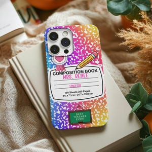 May include: A colorful phone case with a composition book design. The case features a rainbow-colored background and the text "COMPOSITION BOOK MRS. RENEE ENGLISH". It also includes the text "BEST TEACHER EVER!" and measurements of 9¾ x 7½ inches.