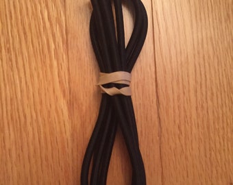 Op de afbeelding: Een bundel zwarte elastische koord, gebonden met een elastiek.