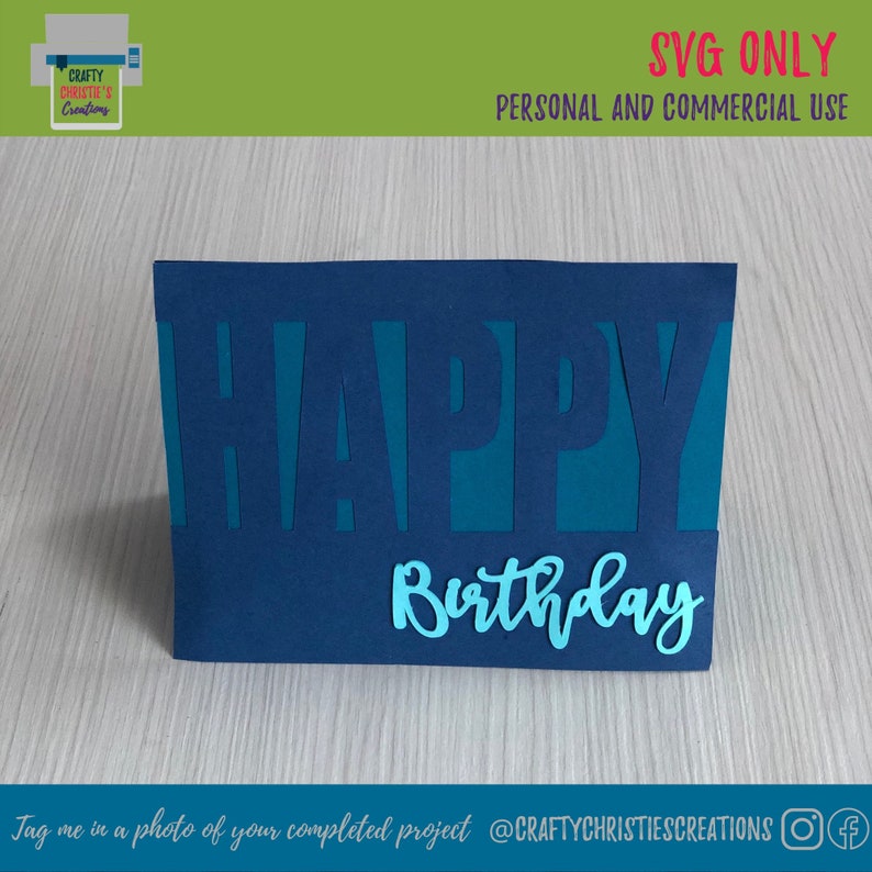 Op de afbeelding: Een blauwe kaart met de woorden "HAPPY Birthday" uitgesneden in turquoise. De kaart ligt op een houten oppervlak.